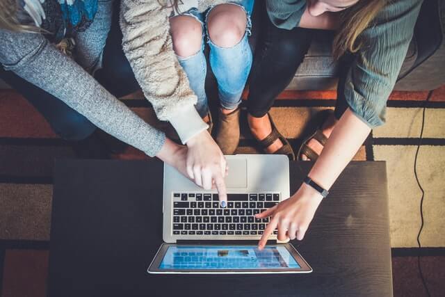 Three people looking at a computer, discussing how to improve customer satisfaction using Net Promoter Score (NPS).