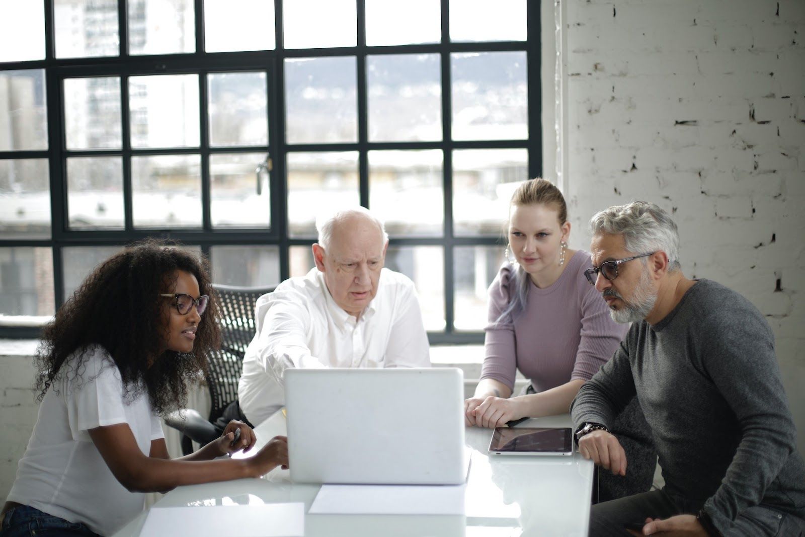 Four people gathered around a laptop comparing Qualtrics competitors.