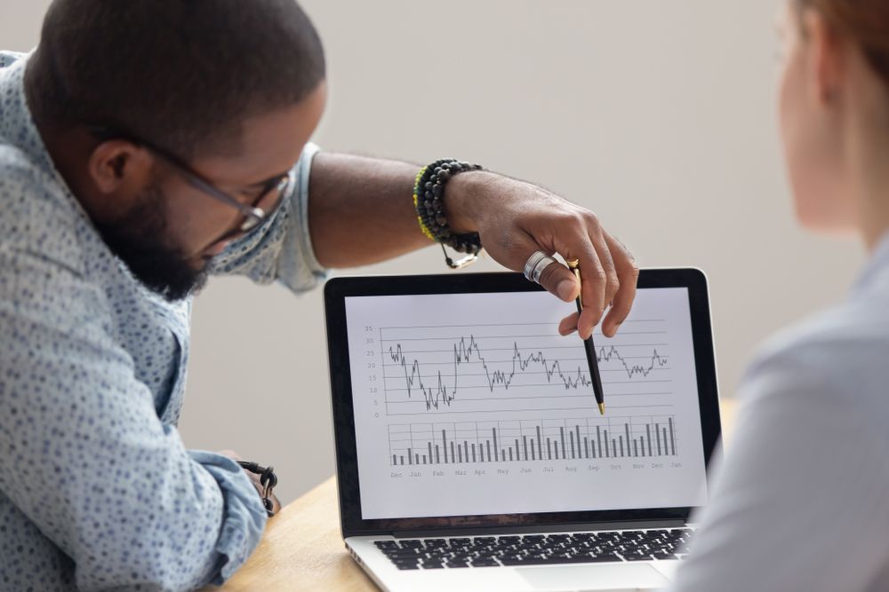 Analyst showing colleague a report analyzing data on his laptop screen