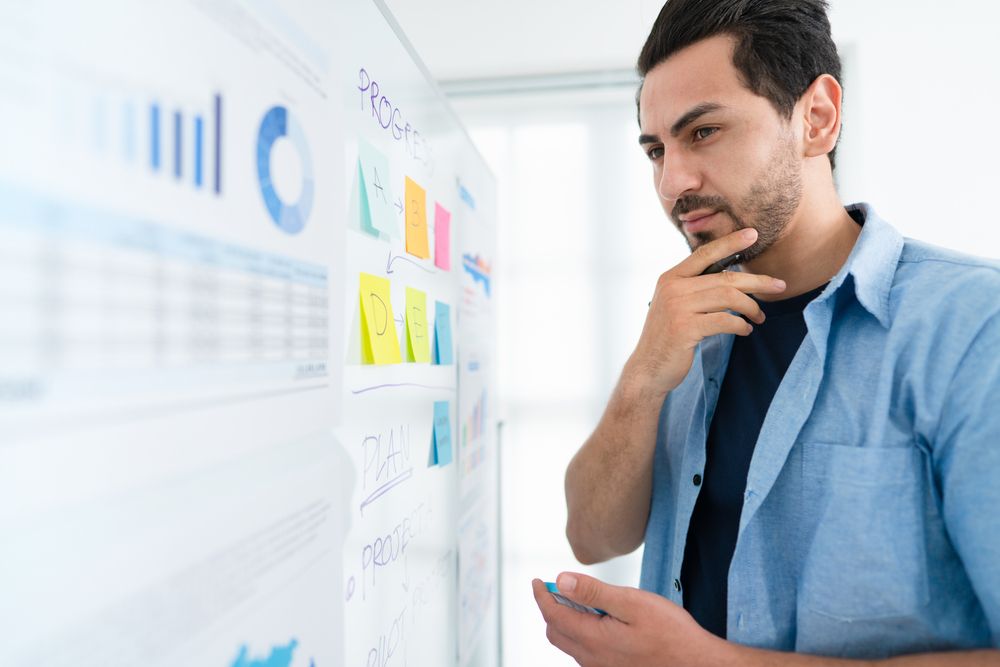 Man looking at charts and notes on a whiteboard