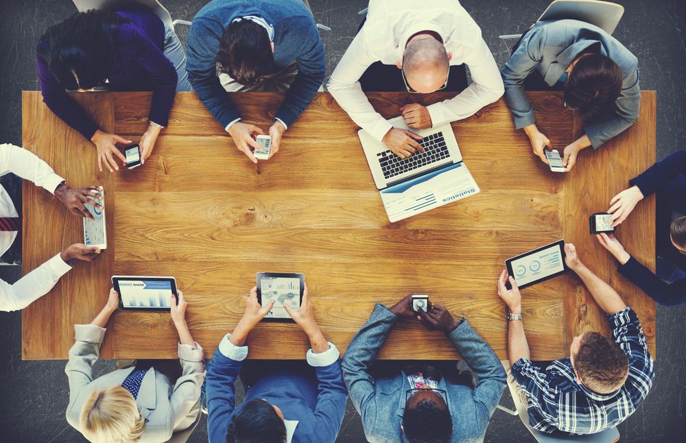 Group of professionals looking at data analysis on their individual devices