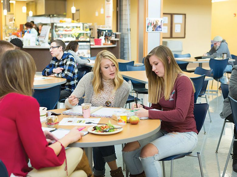 Students studying over lunch in a cafeteria.